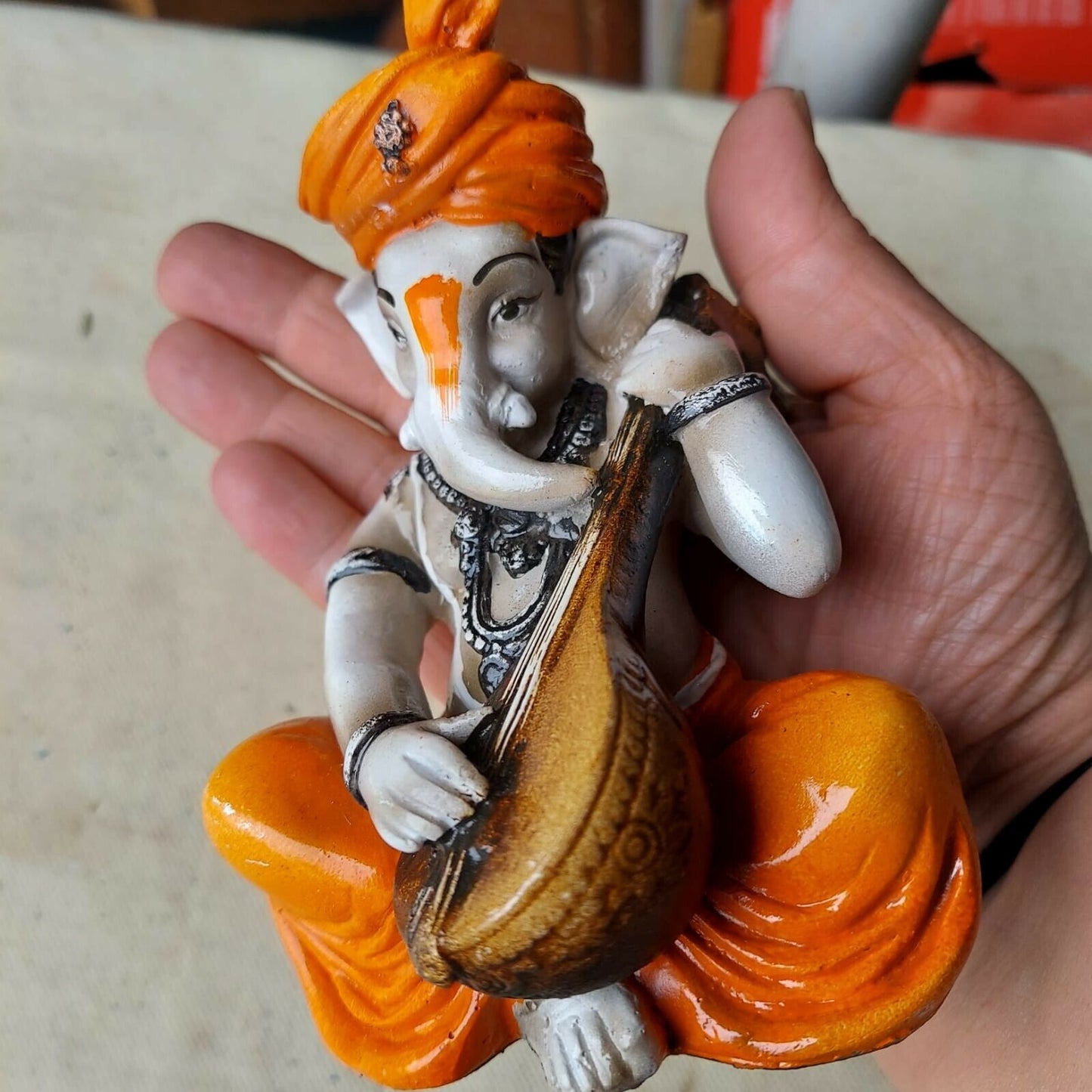 Karigaari India Karigaari Polyresine Ganesha Playing Instrument Orange Figurine